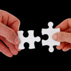 Zwei Menschen halten zwei passende Puzzleteile zueinander