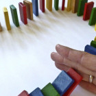 Reihe von Dominosteinen, die durch eine Hand unterbrochen wird.