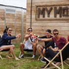 Festivalbesucher sitzen vor einer Holzhütte in Klappstühlen.
