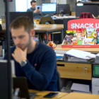 Ein Mann sitzt vor seinem PC im Hintergrund ist eine Box mit Snacks zu sehen.