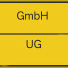 Auf einem gelben Schild steht oben GmbH und auf der Unterseite UG.