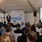Grow up Boutique-Studio-Kongress – Ein Mann steht vor einer Leinwand und hält eine Rede vor Publikum.