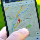 Eine Hand hält ein Handy. Geöffnet ist eine Karte auf Google Maps.