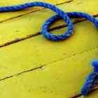Blaues Seil liegt auf gelbem Untergrund.