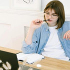 Frau sitzt vorm Laptop und überlegt.
