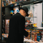 Ein älterer Mann mit Hut steht am Verkaufsfenster eines Kiosk.