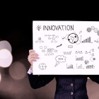 Eine Person hält ein Plakat mit der Aufschrift Innovation in den Händen.