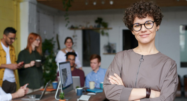 Eine selbstbewusste Unternehmerin steht vor Ihrem Team