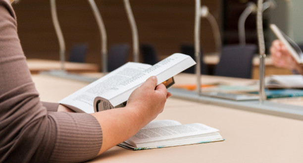 Frau liest ein Buch in einer Bibliothek