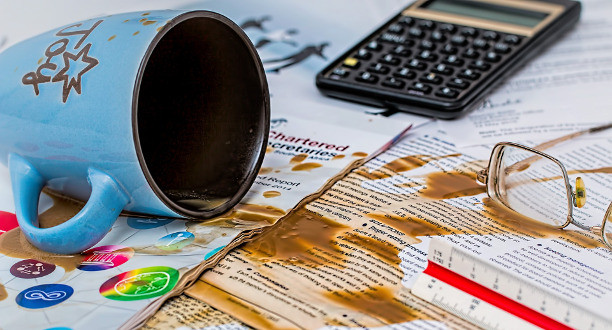 Eine umgefallene Kaffeetasse auf Arbeitsunterlagen