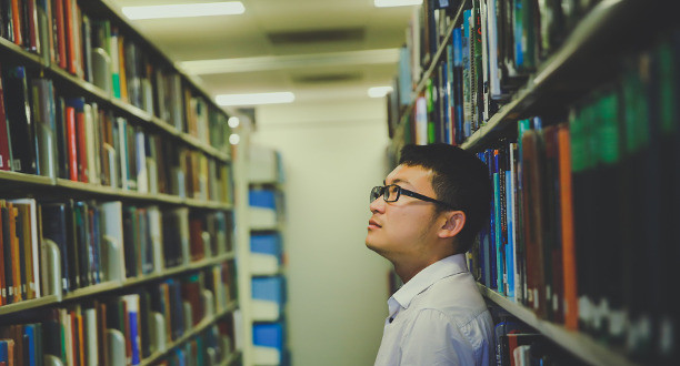 Ein Mann steht im Gang einer Bibliothek