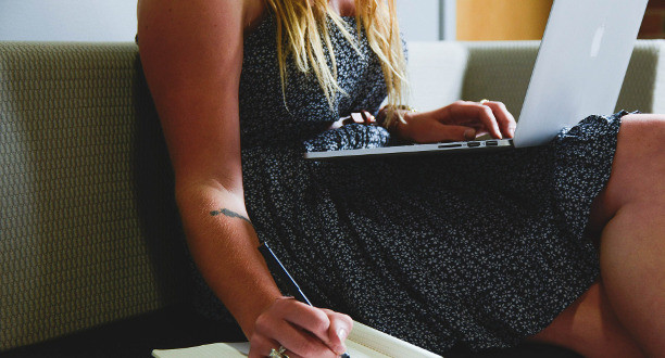 Frau sitzt mit Laptop auf einem Sofa