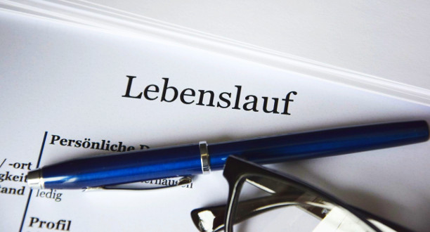 Nahaufnahme eines Lebenslaufs, auf welchem ein Stift und eine Brille liegen.