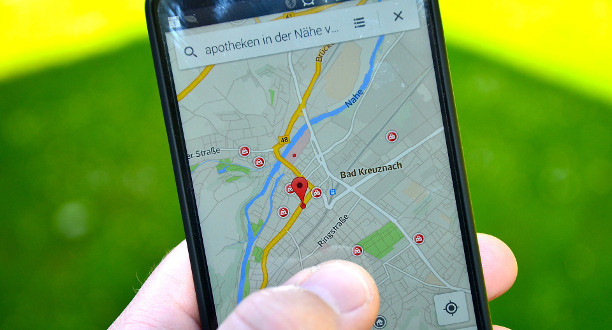 Ein Mann hält ein Handy auf dem eine Google-Maps-Karte geöffnet ist.