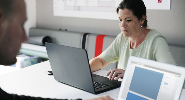 Eine Frau sitzt an einem Laptop und arbeitet.