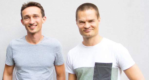Zwei Gründer von Yolife stehen nebeneinander vor einer grauen Wand.