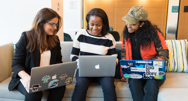 Drei Frauen sitzen mit ihrem Laptop nebeneinander auf einem Sofa.