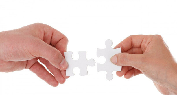 Zwei Händer halten zwei Puzzelteile.