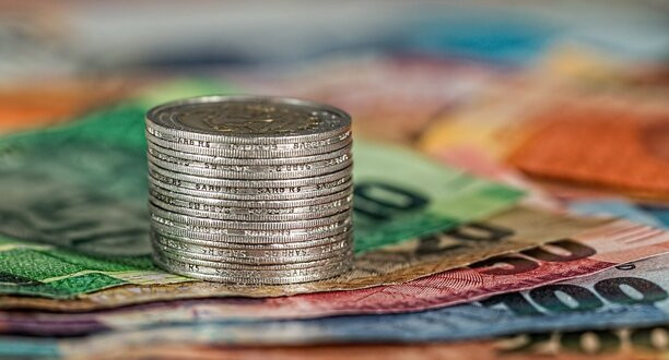 Münzstapel liegt auf Euroscheinen.