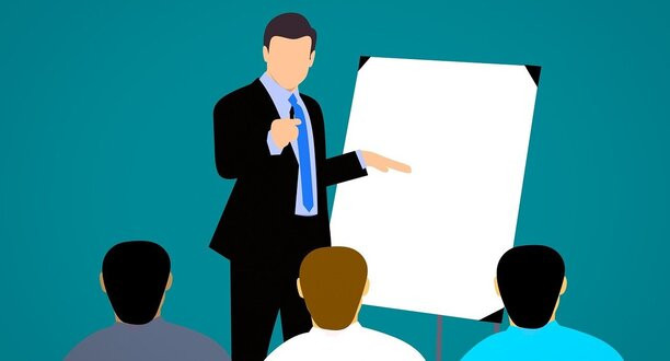 Mann steht vor drei Personen und erklärt etwas an einem Whiteboard.