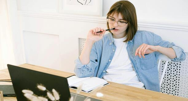 Frau sitzt vorm Laptop und überlegt.