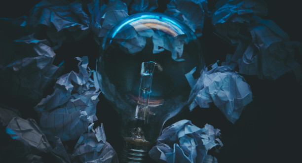 Eine blau reflektierende Glühbirne liegt in einem Haufen zusammengeknüllten Papier