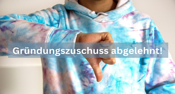 Mann zeigt einen Daumen nach unten. Schrift: Gründungszuschuss abgelehnt.