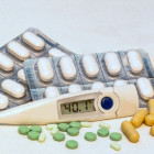 Fieberthermometer und Tabletten auf einem Tisch