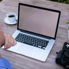 Aufnahme von einem Mann, der an einem Tisch mit seinem Laptop arbeitet.