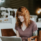 Eine Frau sitzt vor ihrem Laptop und lächelt