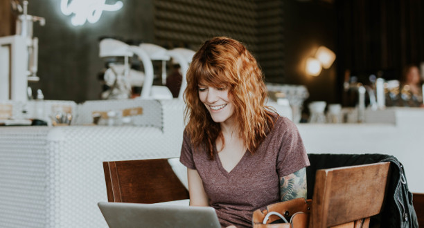 Eine Frau sitzt vor ihrem Laptop und lächelt