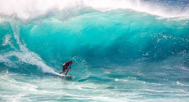 Ein Mann surft auf einer sehr großen Welle.