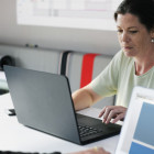 Eine Frau sitzt an einem Laptop und arbeitet.