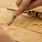 Ein Mann bearbeitet ein Holzstück mit einem Hobel.