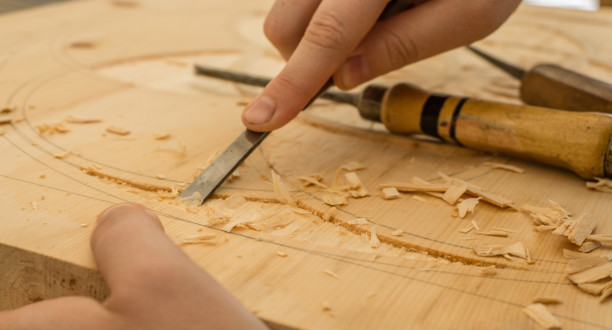 Ein Mann bearbeitet ein Holzstück mit einem Hobel.