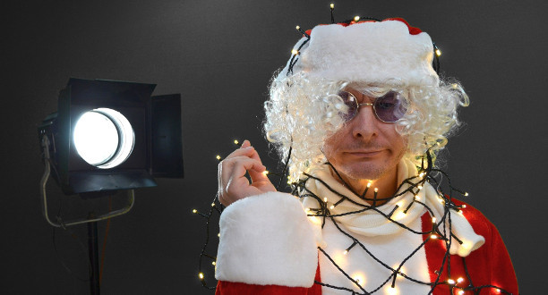 Ein Mann in Weihnachtsmann-Outfit trägt eine Lichterkette um den Hals.