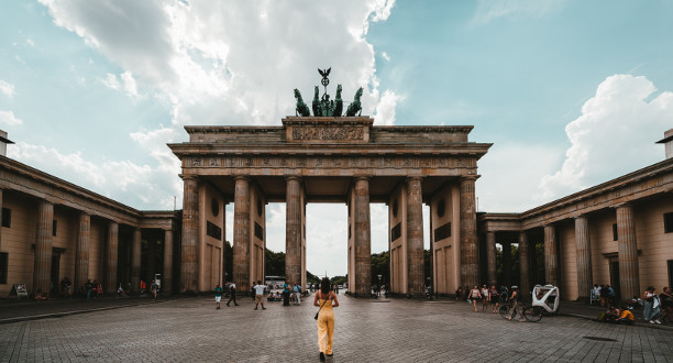 Aufnahme des Brandenburger Tors. Im Vordergrund steht eine Frau mit einem gelben Kleid.