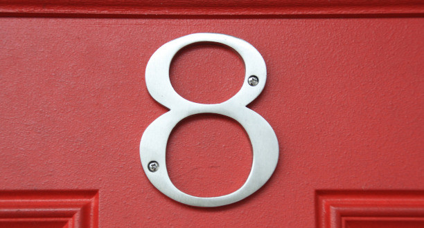 Die Zahl Acht als Hausnummer an einer roten Tür.