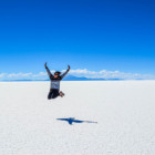 Frau springt hoch. Hintergrund: blauer Himmel und weiße Wüste.