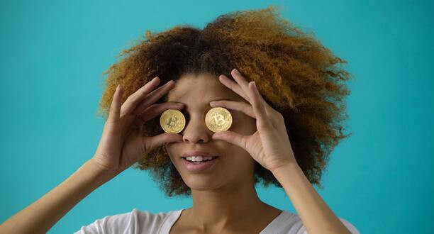 Frau hält zwei Münzen vor ihre Augen.