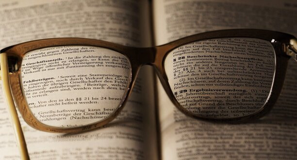 Eine Brille liegt auf einem alten Buch.