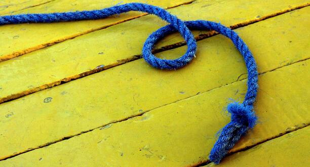 Blaues Seil liegt auf gelbem Untergrund.