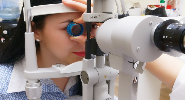 Optiker kontrolliert Auge einer Kundin.