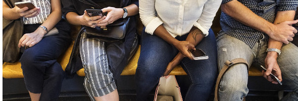 Menschen mit Handys in der Hand sitzen in der Bahn