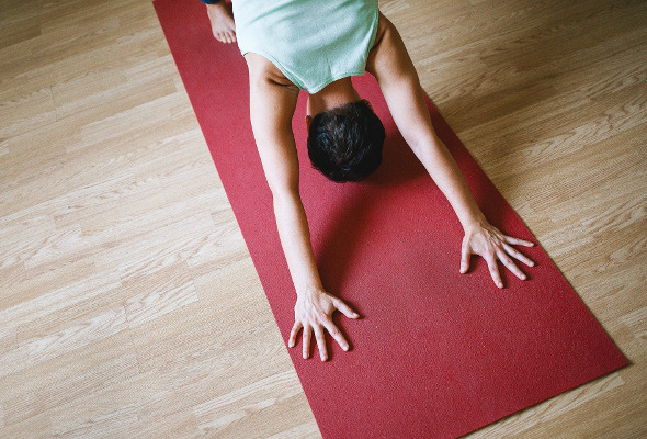 Frau sitzt auf einer roten Yogamatte