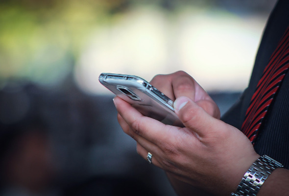 Mann hält ein Handy in seiner Hand.