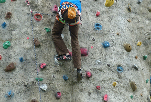 Eine Person klettert eine Kletterwand hoch. 