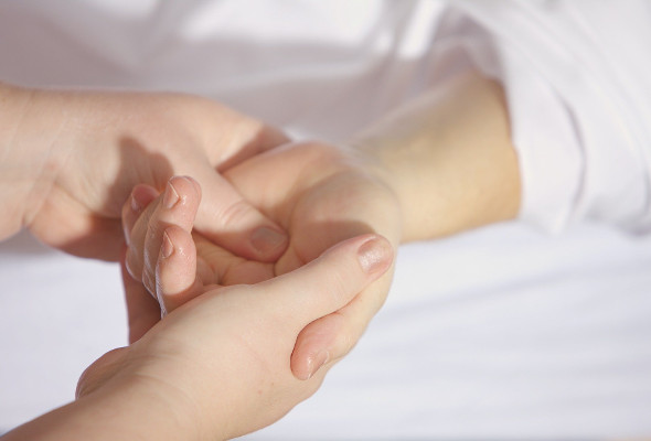 Eine Frau hält die Hand von ihrem Kind, welches ein weißes Oberteil an hat.