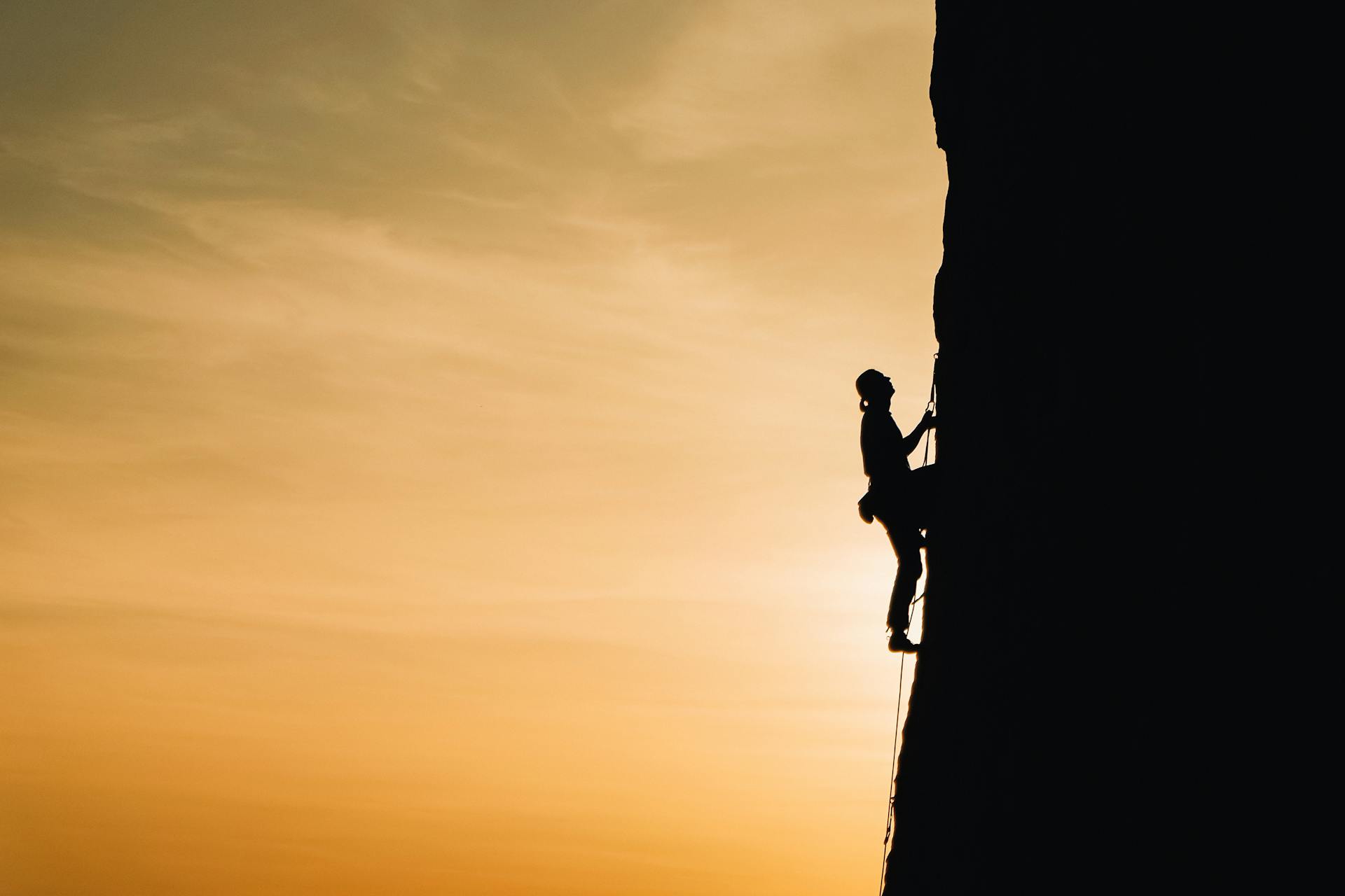 Eine Person klettert eine Steilwand hoch.