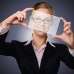 Frau hält eine Folie vor ihr Gesicht.
